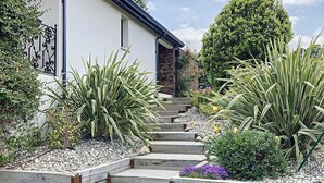 A pathway leading to a building with a stone facade and a metal gate.