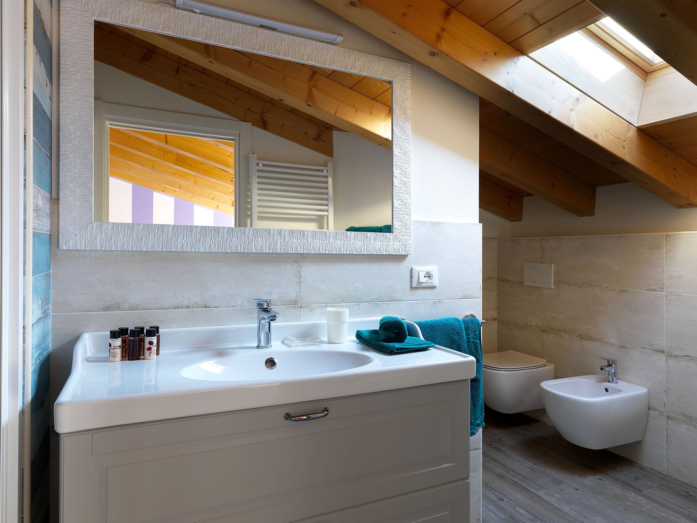 Ein Badezimmer mit Waschbecken, Spiegel und Holzbalkendecke.