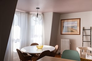A dining area with a round table, chairs, a vase, and a framed picture on the wall.