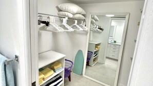A neatly organized closet with shelves, hanging space, and a mirror.