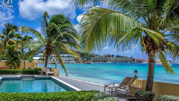 A pool area with a view of the ocean and a resort building in the background.