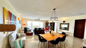 A spacious living area with a dining table, sofas, and a TV.