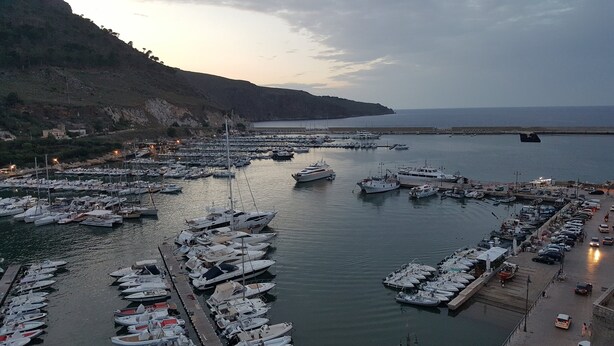 A marina with numerous boats docked, a hilly landscape in the background, and a clear sky. - Mami "Holiday House" (Castellammare del Golfo)