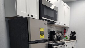 Une cuisine avec des meubles blancs, un réfrigérateur en acier inoxydable, un four à micro-ondes et une cuisinière.