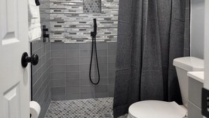 Une salle de bain avec douche, toilettes et un mur recouvert de carreaux décoratifs.