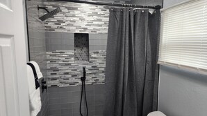 Une salle de bain moderne équipée d’une douche, de toilettes et d’un porte-serviettes.