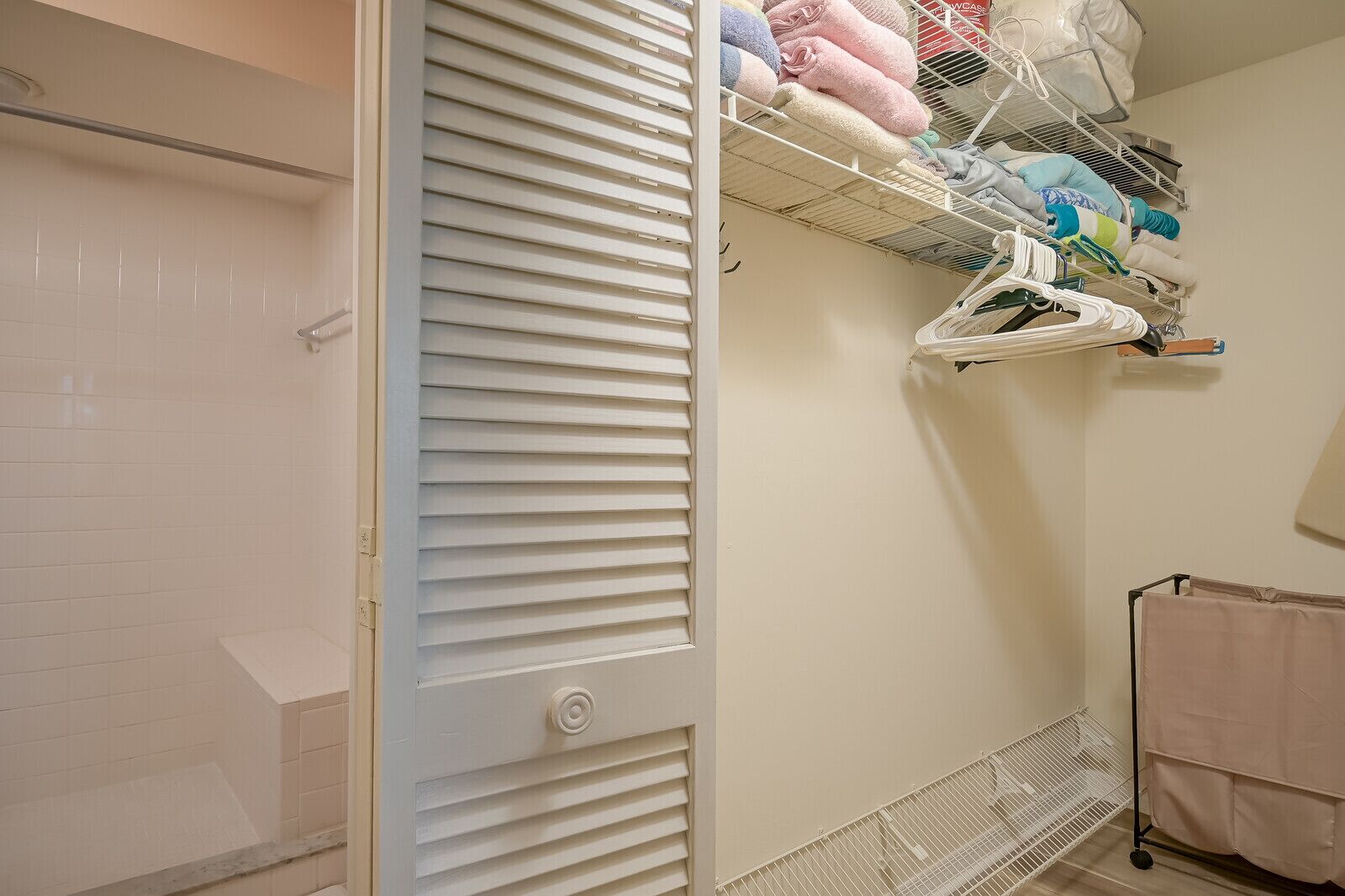 A bathroom with a white door, a towel rack with folded towels, and a shower area.