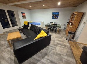 Una sala de estar con un sofá negro, una mesa de madera y un comedor con sillas y una mesa.