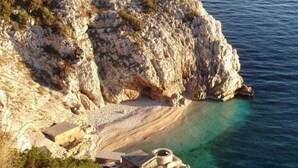 Eine Küstenklippe mit Strand und einem kleinen Gebäude am Wasserrand.