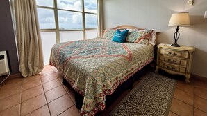 Una camera da letto con un letto grande, un comodino, una lampada, una finestra con tende e un tappeto decorato.