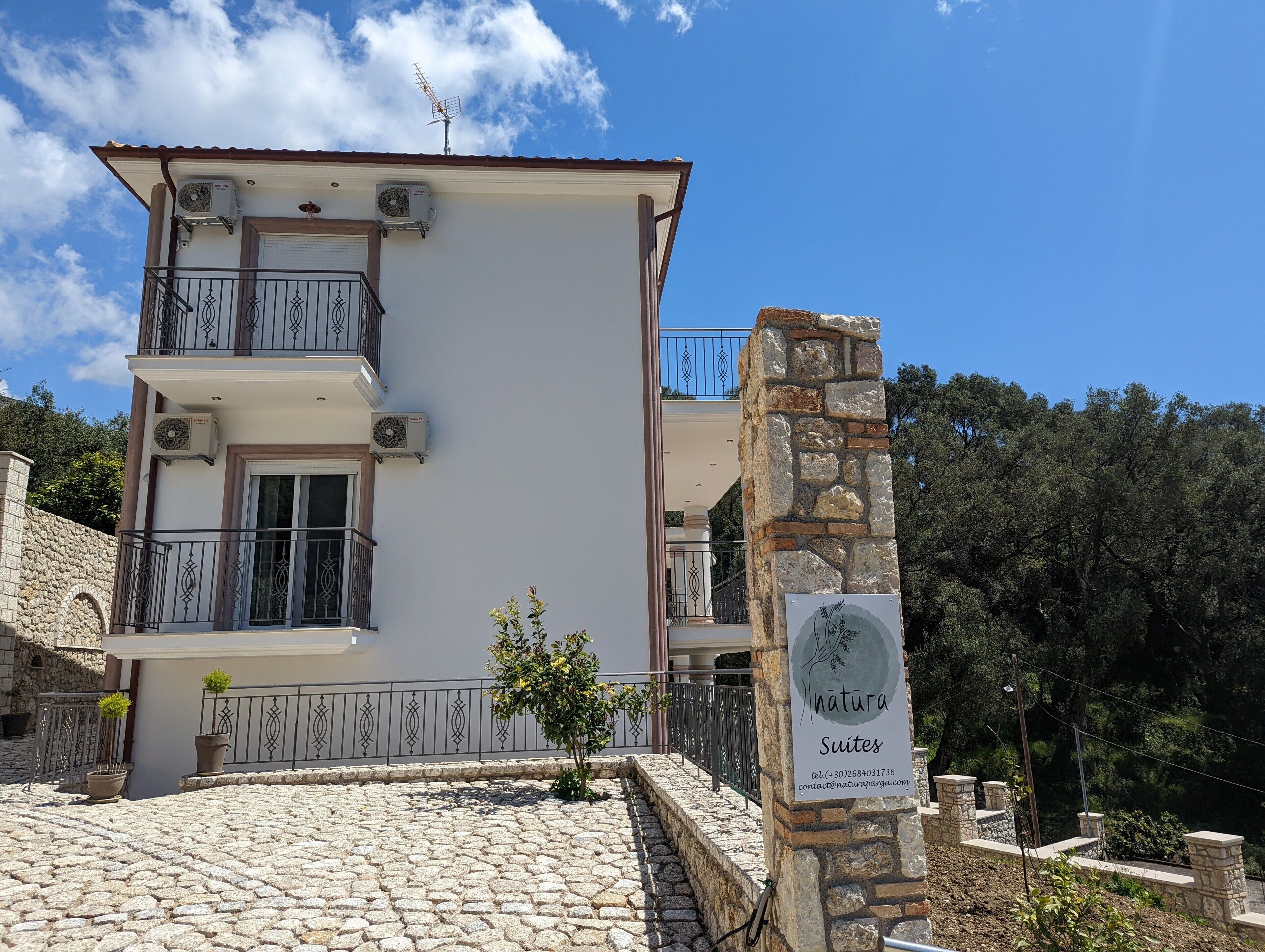 A multi-story building with balconies, air conditioning units, and a stone pillar with a sign.