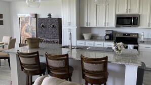 Una cocina moderna con armarios blancos, encimera de granito, horno de acero inoxidable y cafetera.