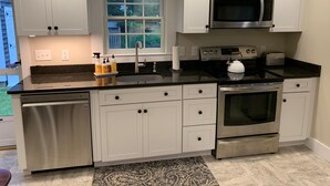 Une cuisine moderne avec des armoires blanches, des appareils en acier inoxydable et un comptoir noir.
