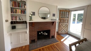 Un salon avec une cheminée, des étagères à livres, un miroir et une porte en bois.