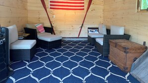 Une pièce chaleureuse, meublée de meubles en osier, avec un tapis à motifs bleus, un drapeau américain et une enseigne indiquant « Port de Harwich ».