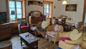 A cozy living room with wicker furniture, a dining table, and a television.