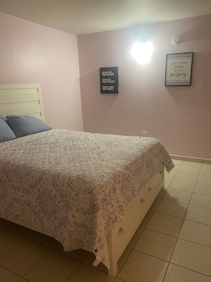 Une chambre à coucher avec un lit, une table de chevet, une horloge murale et des affiches motivantes.