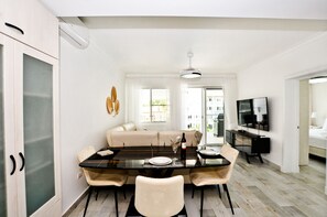 Uma área de jantar moderna com mesa de vidro, cadeiras e um sofá.