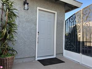 Enter a secure, welcoming space with a traditional door, black metal gate, and a touch of greenery.