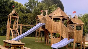 A wooden playground with slides and climbing structures.