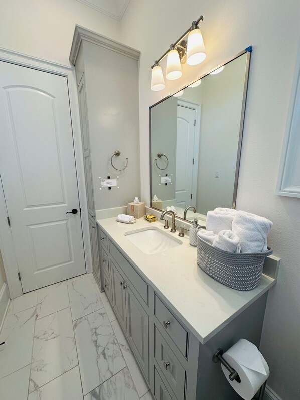 A bathroom with a white sink, a large mirror, and a vanity with drawers.