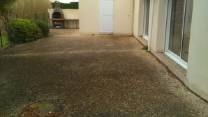 Un camino pavimentado que lleva a una casa con techo de tejas, una puerta y una ventana.