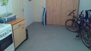 Una cocina con estufa, un armario de madera y un contenedor azul.