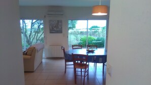 Un área de comedor con una mesa y sillas, un radiador y un ventanal con vistas a zonas verdes.