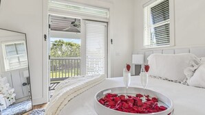Ein Schlafzimmer mit einem Bett, einem Nachttisch mit zwei Sektgläsern und einer Schale voller Rosenblätter.