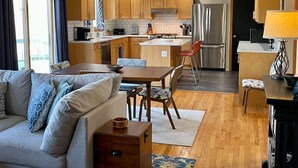 A modern kitchen with wooden cabinets, a stainless steel refrigerator, and a dining area with a table and chairs. - Welcoming retreat close to Cornell, Ithaca College, and Cayuga Lake (Ithaca)