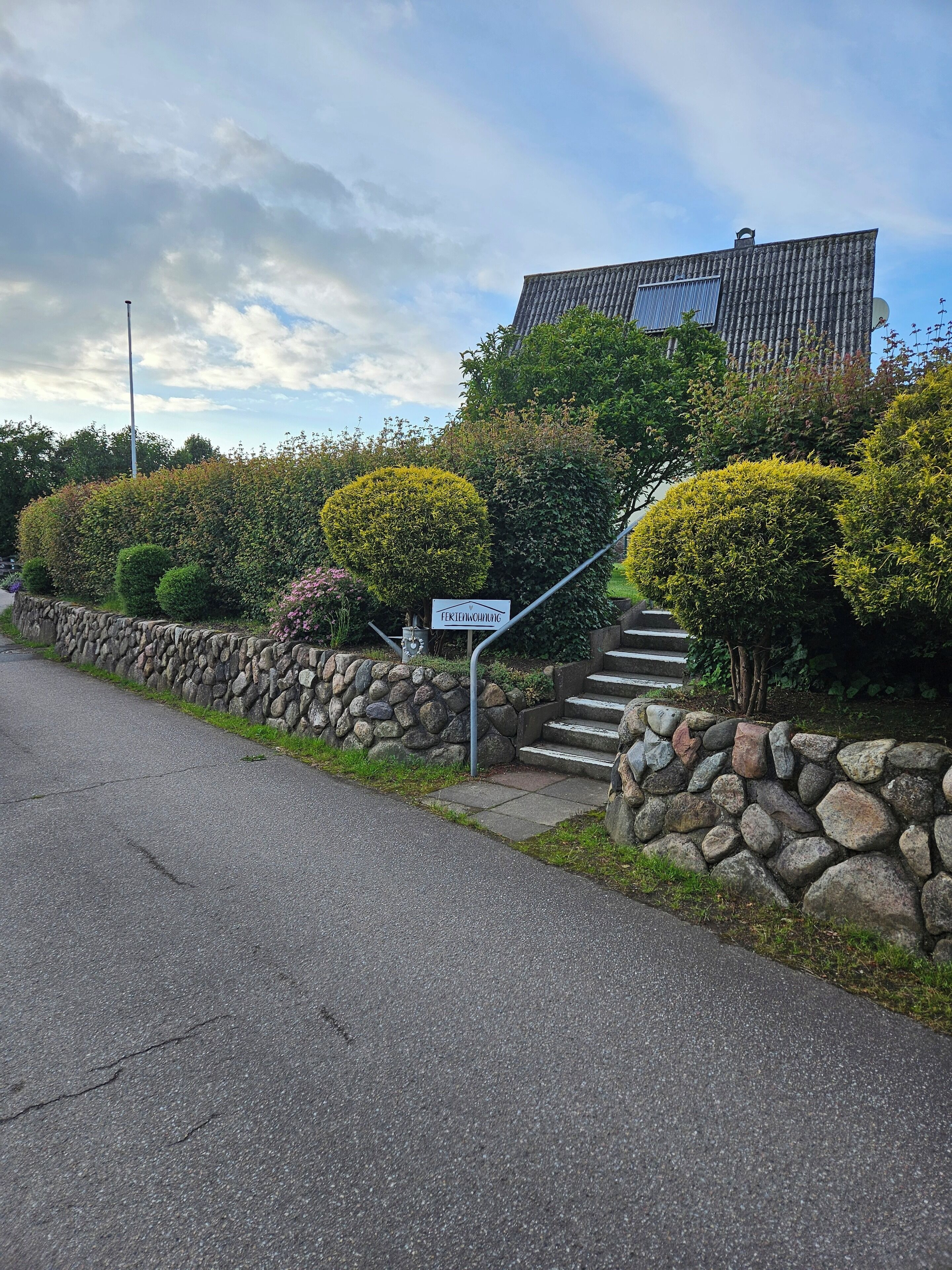 A stone wall leading to a building with a sign that reads "Fertigungsverwaltung".