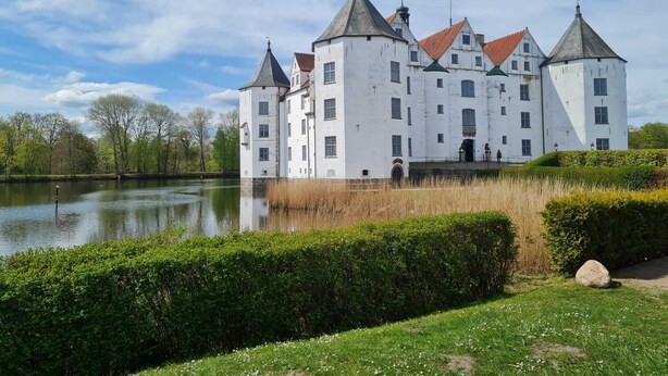 Eine große, weiße Burg mit zahlreichen Türmen und einem Burggraben.