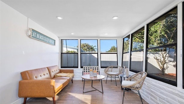 A sunlit room with a leather sofa, two wicker chairs, a small round table, and large windows offering a view of the outdoors. - Fort Lauderdale House (Fort Lauderdale)