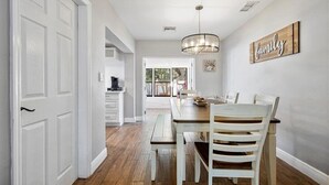 A dining area with a wooden table and white chairs, a chandelier, and a 'family' sign on the wall. - Fort Lauderdale House (Fort Lauderdale)