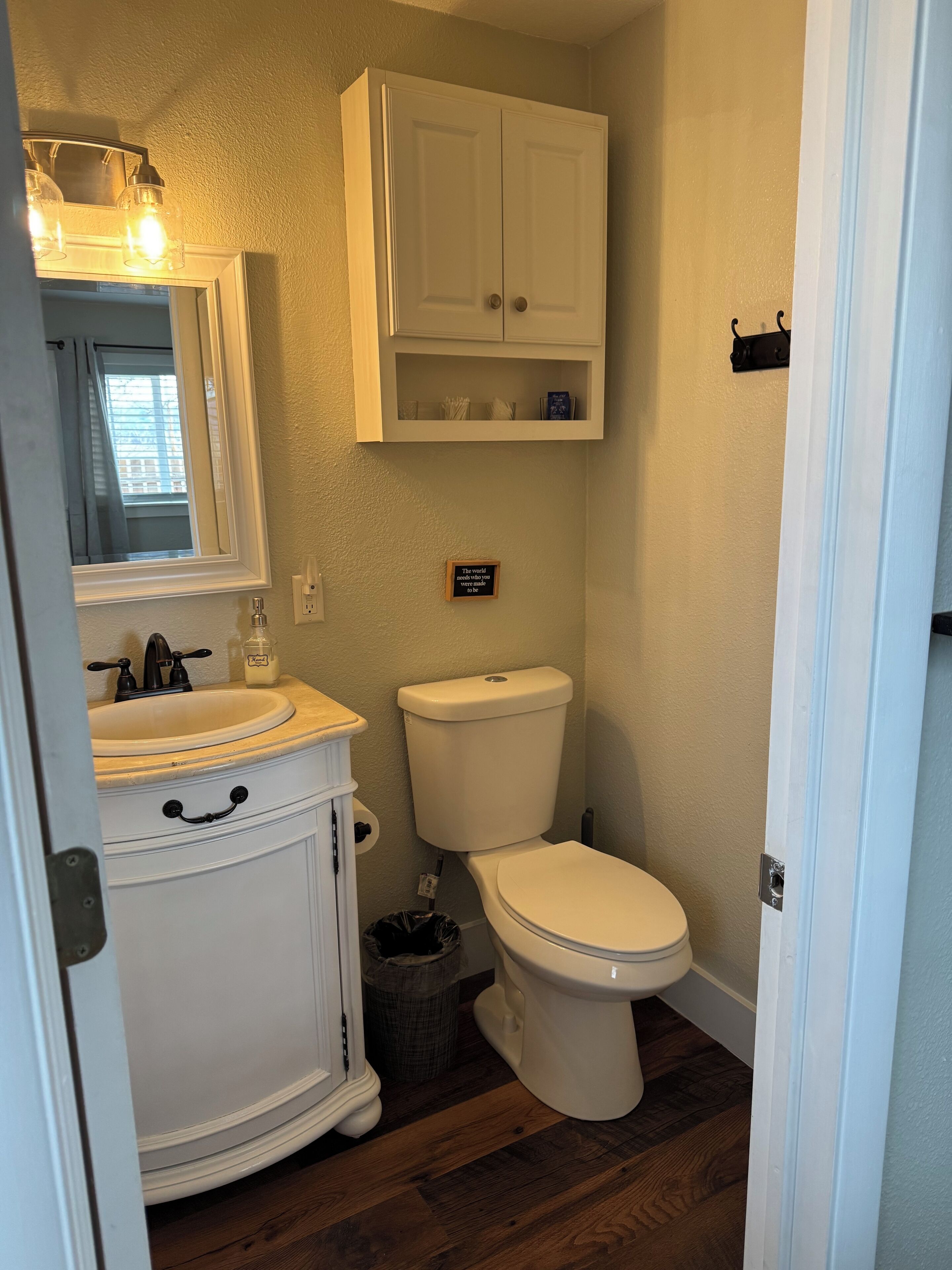 A bathroom with a white vanity, a toilet, and a cabinet above the toilet.