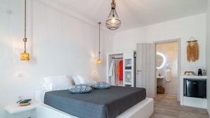 A modern bedroom with a large bed, bedside tables, a wardrobe, a small kitchenette, and a bathroom with a mirror and towel rack. - ISLAND CONCEPT CHANIA (Chania)