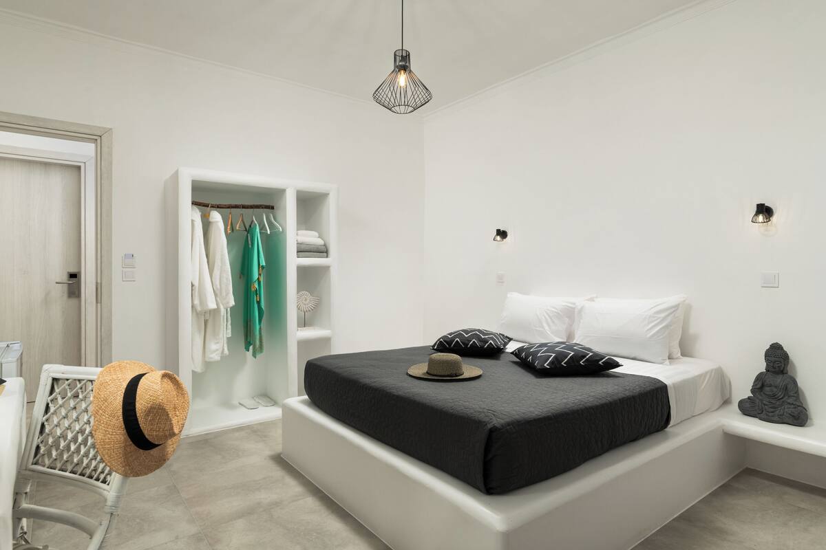 A modern bedroom with a large bed, a wardrobe, and a small statue.