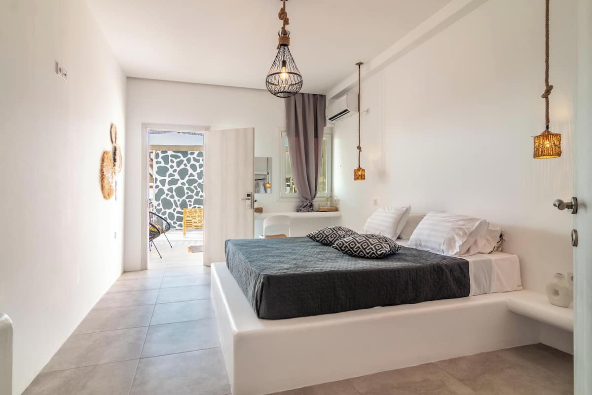 A modern bedroom with a large bed, a small desk, and a view of the outside.