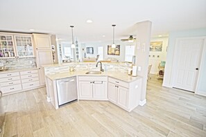A spacious kitchen with white cabinetry, a central island, and a large window.