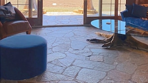 A rustic interior with a stone floor, wooden furniture, and a large glass door leading to a mountain view. - Glass Cottage Overlooking Beartooth Mountain Range (Roberts)