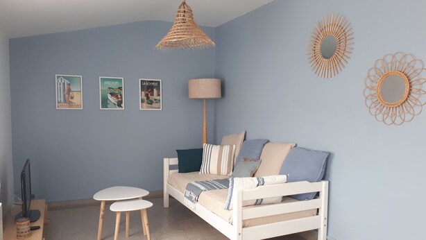 Een moderne slaapkamer met een wit bed, een rond tafeltje en een hanglamp.