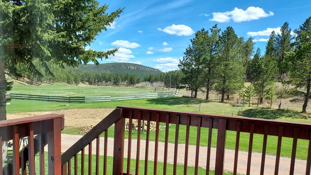 Terraza de madera con vistas a un campo de golf y árboles circundantes.