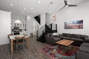 Una sala de estar moderna con un sofá gris, una mesa de centro de madera y una alfombra colorida.