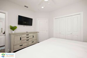 A bedroom with a bed, a dresser, a television, and a closet.