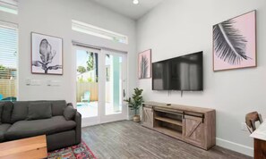 Un soggiorno con un divano grigio, una TV fissata al muro e un mobile TV in legno.