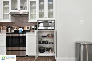 A kitchen with stainless steel appliances, white cabinetry, and a microwave. - Luxury Island Home | Pool, Parking & Walk to Beac (South Padre Island)