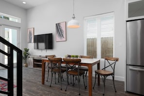 Une cuisine moderne avec une table à manger, des chaises, un téléviseur et un réfrigérateur.
