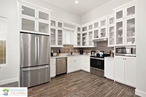 Una cocina moderna con armarios blancos, electrodomésticos de acero inoxidable y piso de madera.