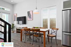 Una cocina moderna con comedor, televisor de pantalla plana y refrigerador de acero inoxidable.
