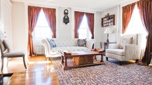 A living room with a sofa, armchairs, a wooden coffee table, and a patterned rug. - The Clipper - 1747 Historic Isaac Pierce House 1st Floor (Somerset)